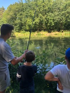 ASV Miesau Ein junger Erwachsener, der zusammen mit einem Jungen eine Angel hält. Daneben ein weiterer Junge. Alle drei stehen am Ufer und schauen auf den See.