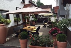 Biergarten Rilli Brehmer Gepflasteter Biergarten vom Gasthaus Rilli-Brehmer mit Tischen und Blumen