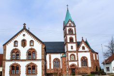 Eine Kirche aus Sandstein mit weißem Putz mit einem grünen Dach.