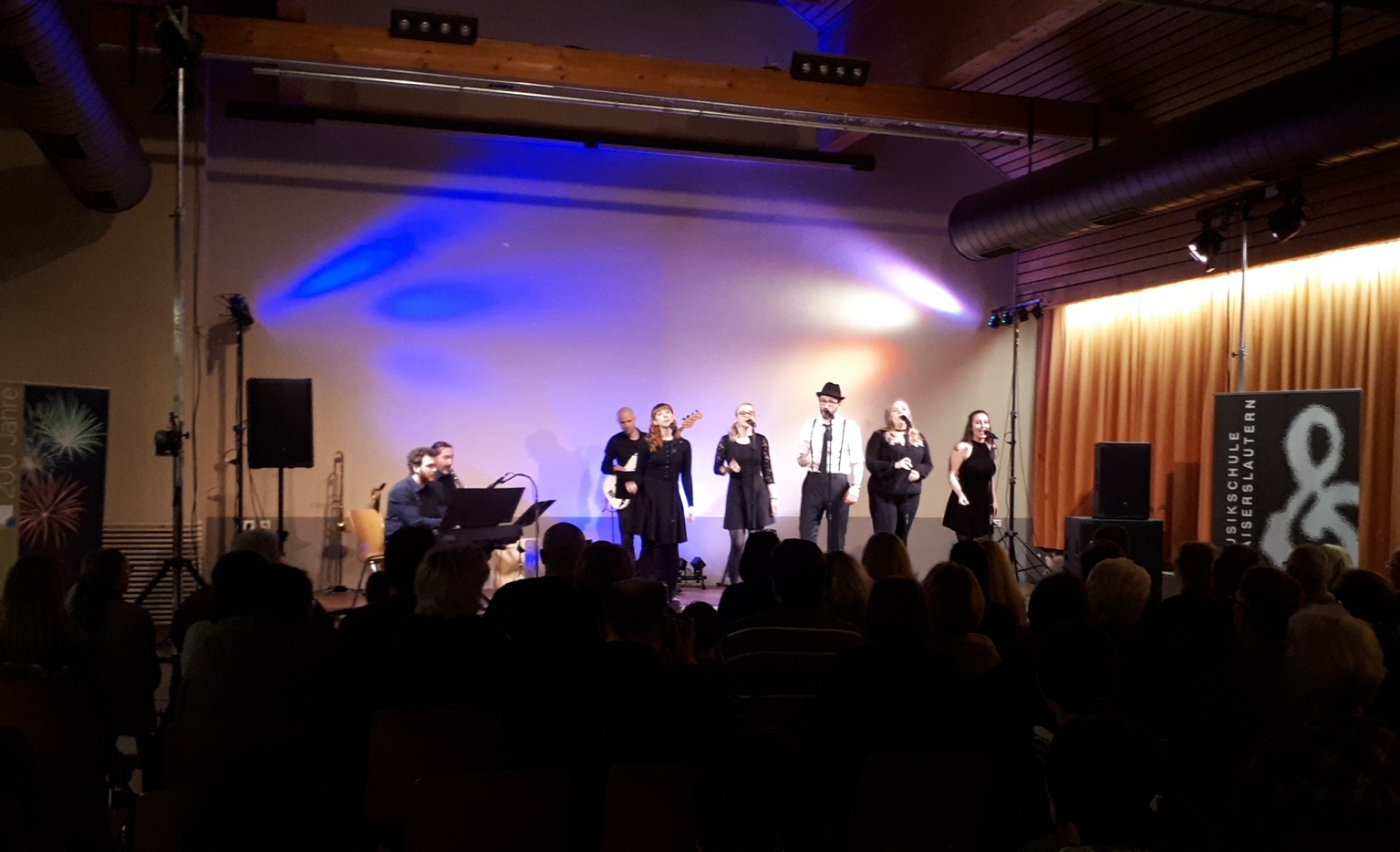 Menschen auf einer Bühne, die Singen und Instrumente spielen