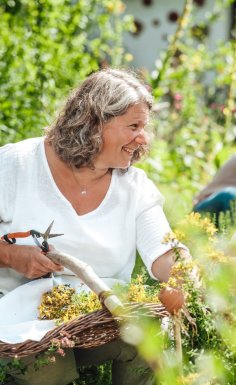 Eine ältere und jüngere Frau mit Körben, die Kräuter sammeln.