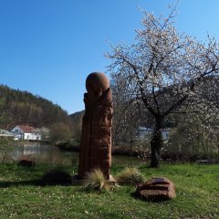 Eine Sandsteinsäule die eine Kugel trägt. Im Hintergrund befindet sich ein See. 
